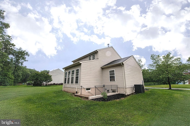 rear view of property featuring a yard, central AC unit, and a wooden deck