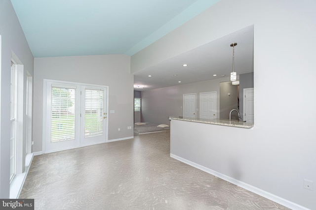 unfurnished living room with plenty of natural light, baseboards, vaulted ceiling, a sink, and recessed lighting