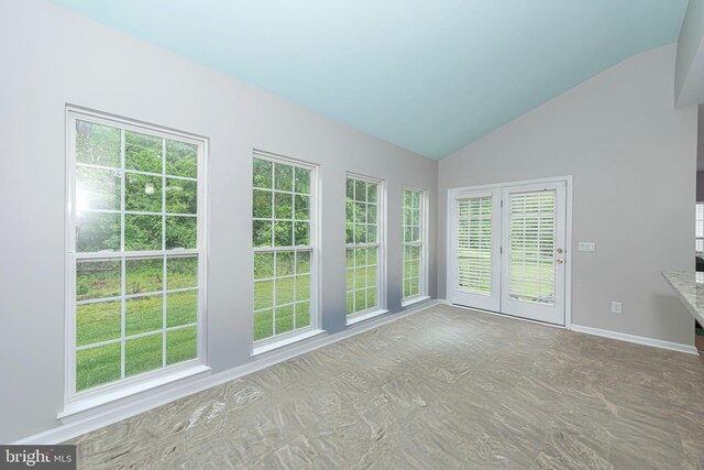 empty room featuring vaulted ceiling and baseboards