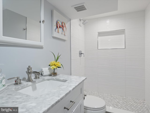 full bathroom featuring toilet, vanity, and a tile shower