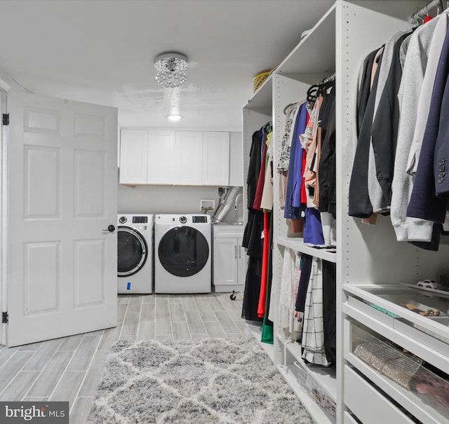 washroom featuring separate washer and dryer, cabinet space, and wood finish floors