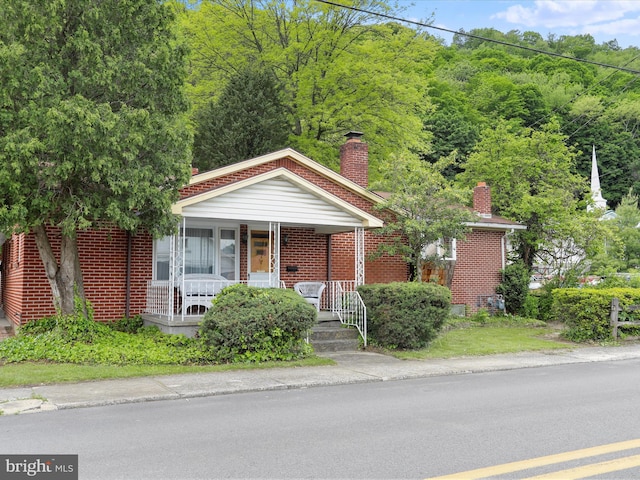 629 W Piedmont St, Keyser, WV 26726 - bungalow featuring a porch, a chimney, and brick siding