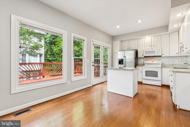 7702 Ousley Pl, Alexandria, VA 22315 - kitchen featuring white appliances, white cabinets, tasteful backsplash, light wood finished floors, and a center island