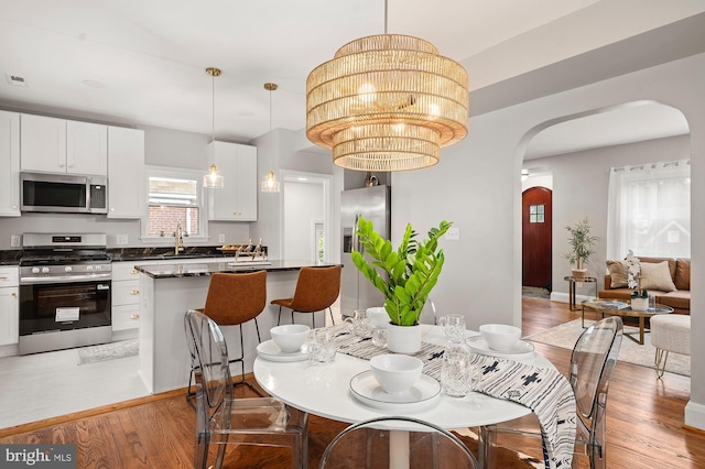 3902 Biddison Ln, Baltimore, MD 21206 - dining space featuring arched walkways, light wood-style floors, and a chandelier