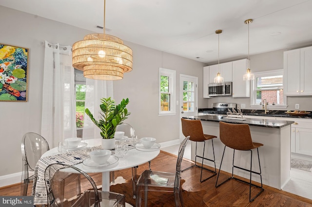 3902 Biddison Ln, Baltimore, MD 21206 - kitchen with stainless steel microwave, stove, dark countertops, wood finished floors, and white cabinetry