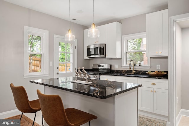 3902 Biddison Ln, Baltimore, MD 21206 - kitchen featuring stainless steel appliances, a sink, baseboards, a breakfast bar, and white cabinets