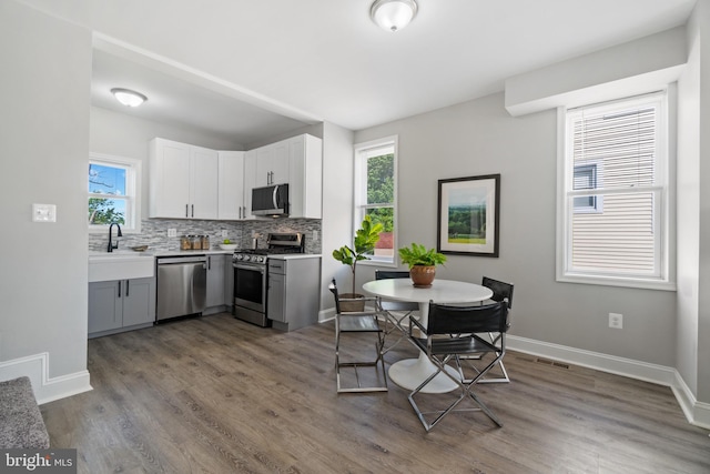 2704 Rueckert Ave, Baltimore, MD 21214 - kitchen featuring stainless steel appliances, decorative backsplash, wood finished floors, and light countertops