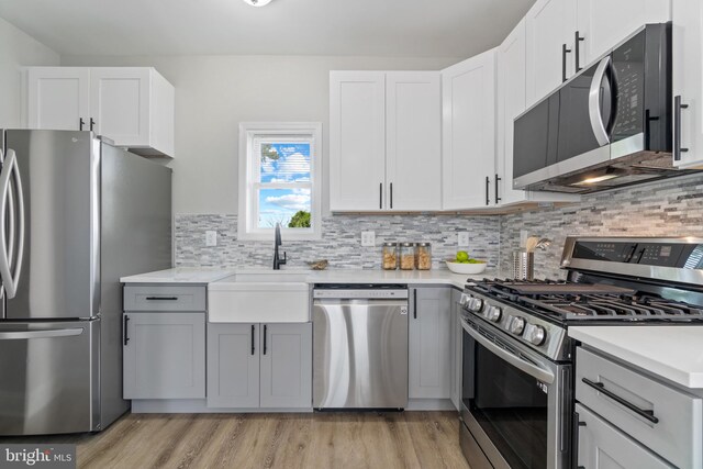 2704 Rueckert Ave, Baltimore, MD 21214 - kitchen with stainless steel appliances, light wood-style floors, light countertops, and tasteful backsplash
