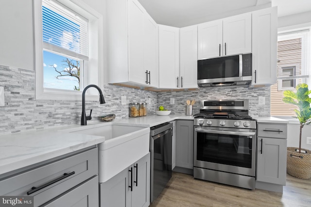2704 Rueckert Ave, Baltimore, MD 21214 - kitchen featuring appliances with stainless steel finishes, light wood-type flooring, gray cabinets, and backsplash