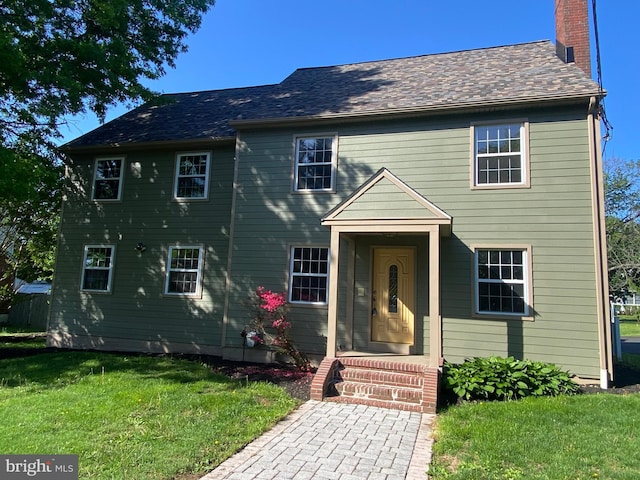 view of front facade with a chimney and a front yard