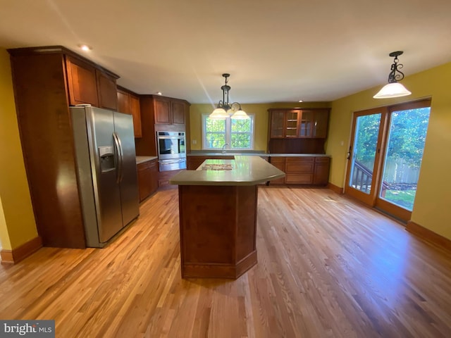 kitchen featuring stainless steel appliances, a warming drawer, light wood-style flooring, glass insert cabinets, and baseboards