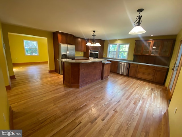 kitchen with stainless steel appliances, light wood-style flooring, and glass insert cabinets
