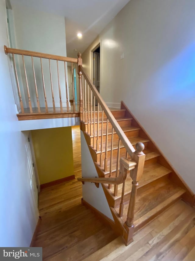 stairway with wood finished floors, baseboards, and recessed lighting