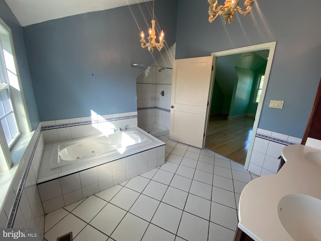 bathroom featuring a chandelier, tile patterned floors, a tile shower, a jetted tub, and vanity