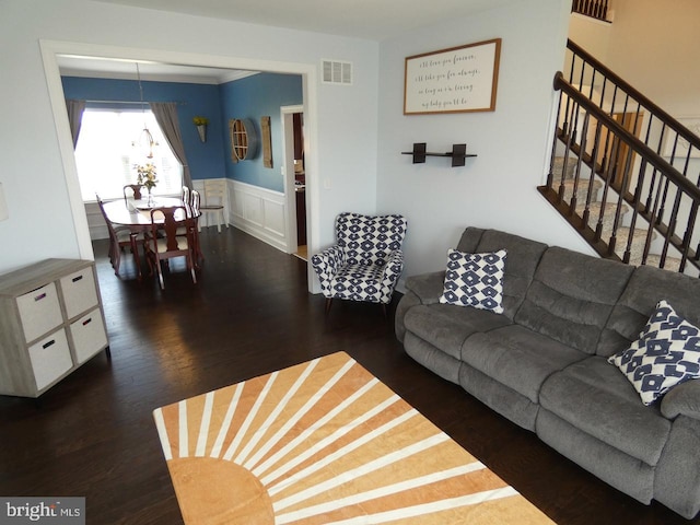living area with wood finished floors, wainscoting, a chandelier, stairway, and a decorative wall