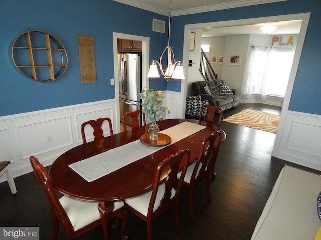 dining space featuring ornamental molding, dark wood-type flooring, a decorative wall, wainscoting, and stairs