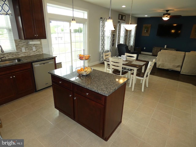 kitchen featuring stainless steel dishwasher, a sink, open floor plan, ceiling fan, and dark stone counters