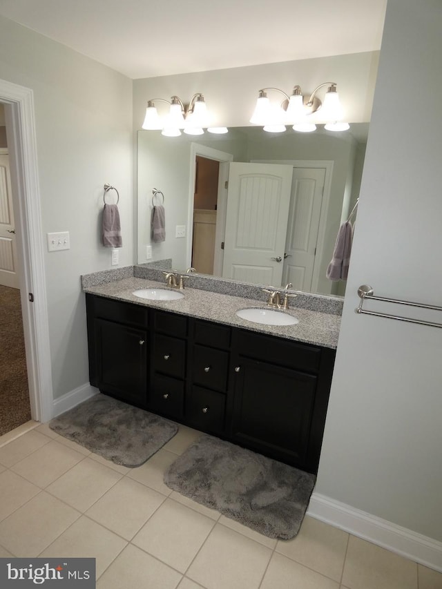 full bath featuring double vanity, tile patterned flooring, and baseboards