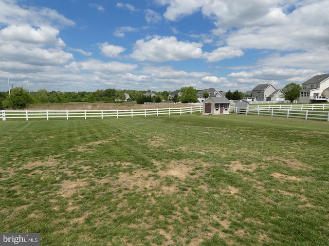 view of yard with a storage unit, an outbuilding, and a rural view