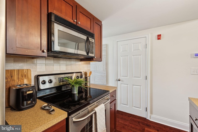 kitchen with stainless steel appliances, backsplash, light countertops, dark wood finished floors, and baseboards