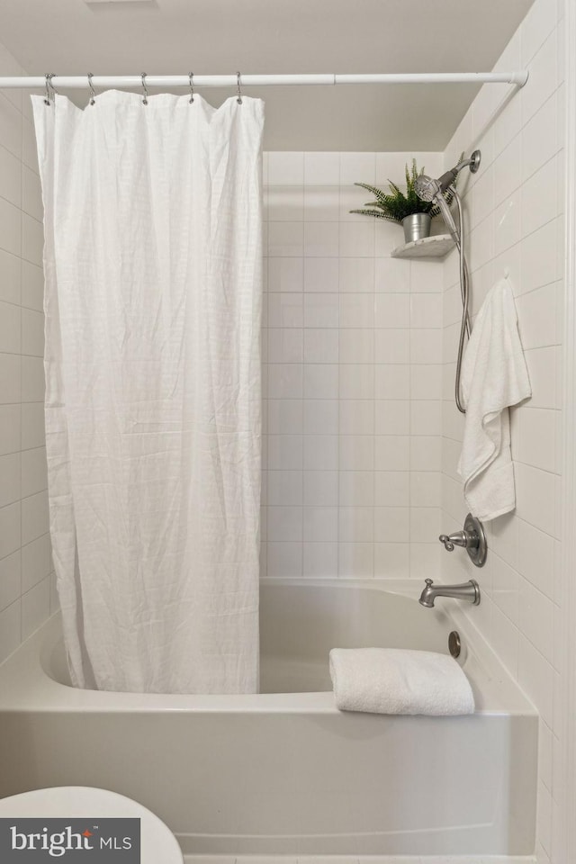 bathroom featuring shower / tub combo and toilet