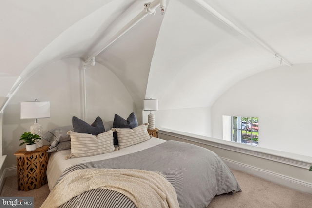 carpeted bedroom with vaulted ceiling and baseboards