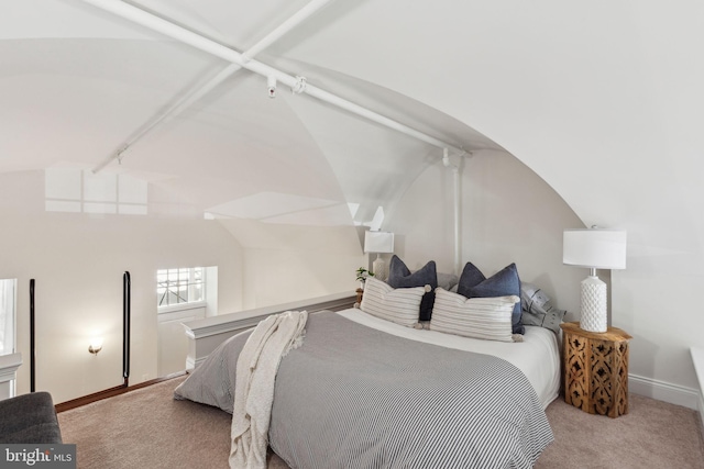 carpeted bedroom with baseboards, vaulted ceiling, and track lighting