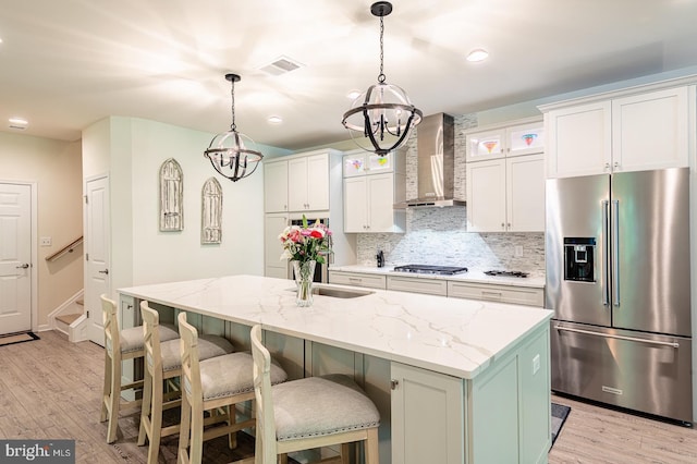 314 Tranquility Way, Middletown, DE 19709 - kitchen featuring stainless steel appliances, wall chimney range hood, a chandelier, light wood finished floors, and decorative backsplash