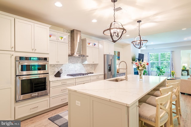314 Tranquility Way, Middletown, DE 19709 - kitchen featuring wall chimney exhaust hood, a sink, appliances with stainless steel finishes, a chandelier, and light wood-style floors