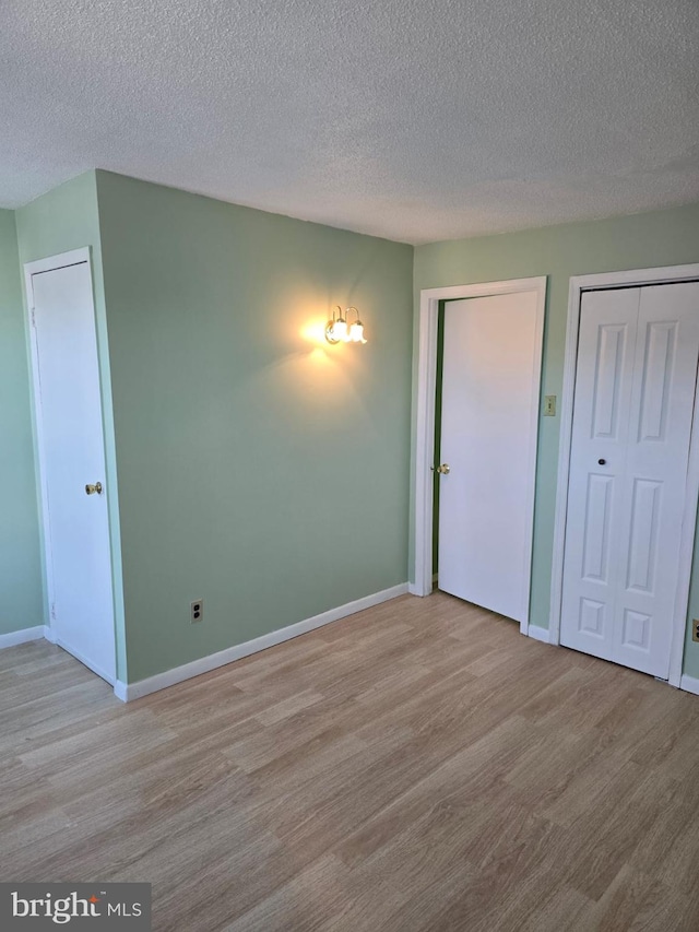 4527 Main St, Whitehall, PA 18052 - unfurnished bedroom with wood finished floors, a textured ceiling, two closets, and baseboards