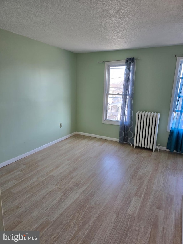 4527 Main St, Whitehall, PA 18052 - empty room with radiator heating unit, healthy amount of natural light, wood finished floors, a textured ceiling, and baseboards