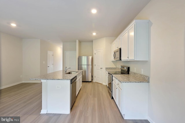 kitchen with appliances with stainless steel finishes, a sink, light wood-type flooring, a center island with sink, and recessed lighting