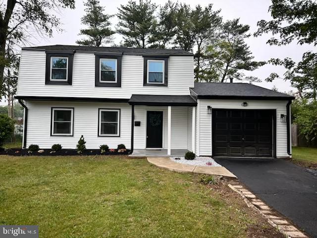 view of front of property featuring asphalt driveway, a garage, and a front yard