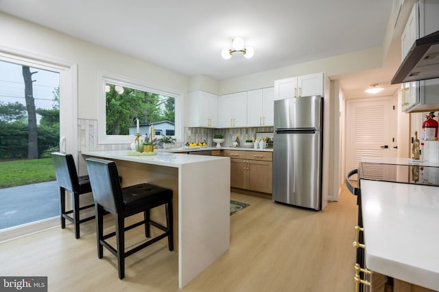 127 Toledo Ln, Willingboro, NJ 08046 - kitchen with freestanding refrigerator, light wood finished floors, a peninsula, and under cabinet range hood