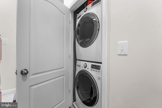 washroom featuring stacked washer / dryer and baseboards