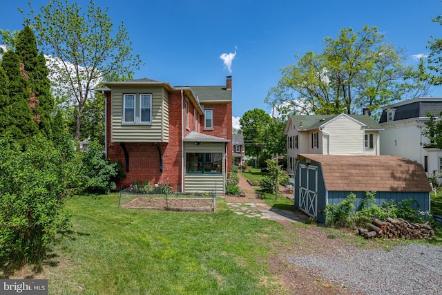 rear view of property with a storage shed, a chimney, an outdoor structure, a lawn, and brick siding