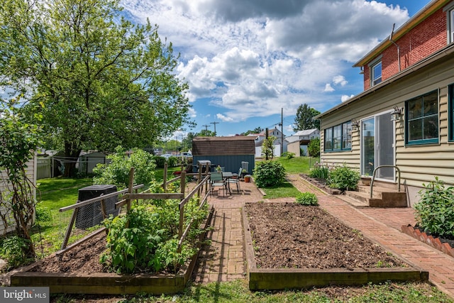 view of yard with a garden, a patio area, an outdoor structure, a storage unit, and fence