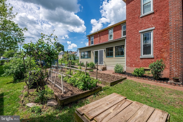 rear view of property featuring a garden, a lawn, and brick siding