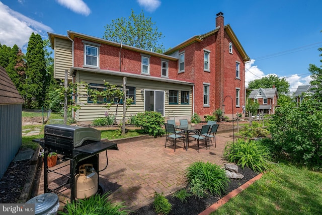 back of property with a patio and brick siding