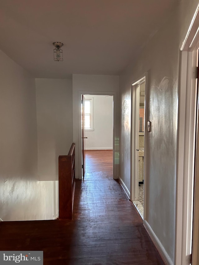 hallway with dark wood finished floors and baseboards