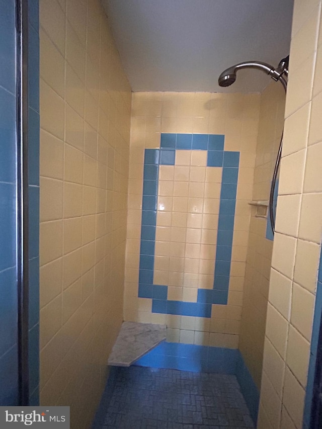 full bath with a tile shower and tile walls
