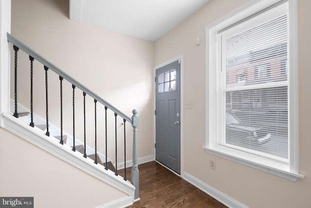 foyer entrance featuring baseboards, dark wood-style floors, and stairway