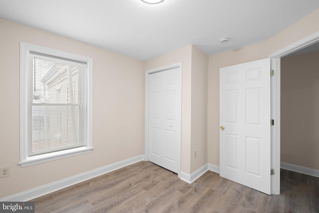unfurnished bedroom with a closet, wood finished floors, and baseboards