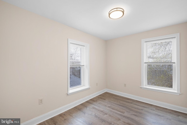 unfurnished room featuring plenty of natural light, wood finished floors, and baseboards