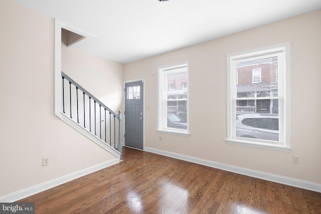 entrance foyer featuring baseboards, wood finished floors, and stairway