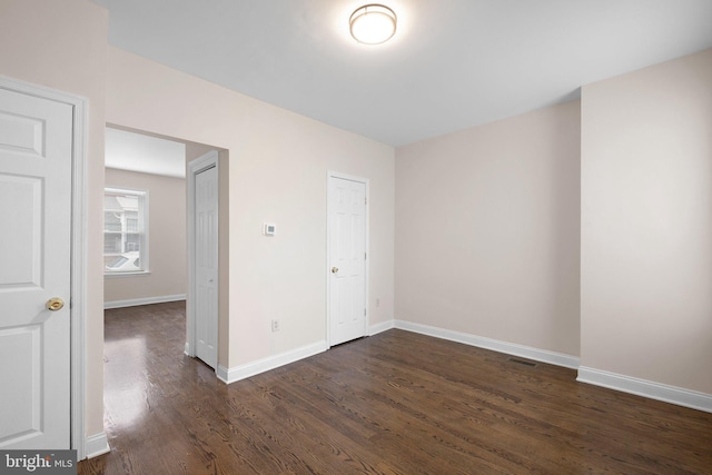 unfurnished bedroom with dark wood-type flooring and baseboards