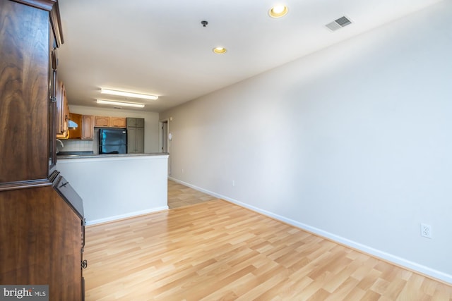kitchen with freestanding refrigerator, light wood-style flooring, baseboards, a peninsula, and recessed lighting