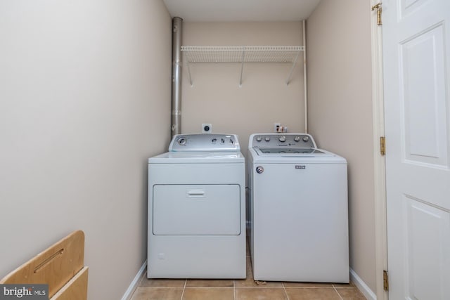 laundry room featuring washer and dryer, light tile patterned flooring, and baseboards