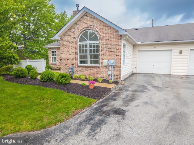view of front of property featuring brick siding, a chimney, an attached garage, driveway, and a shingled roof