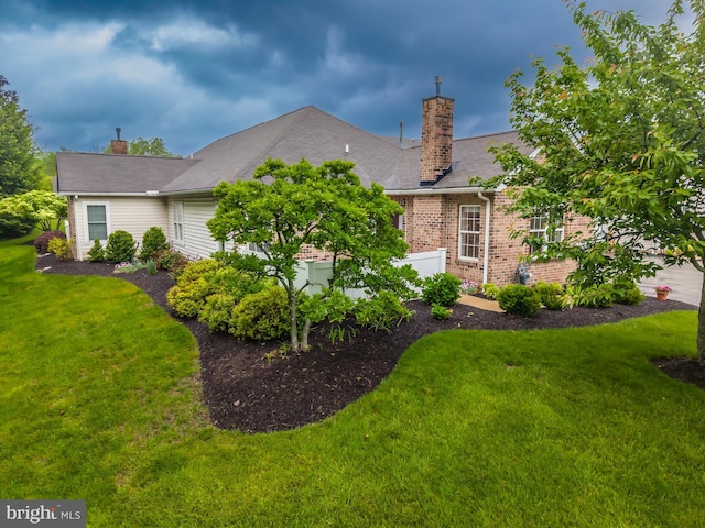 back of house featuring a chimney, a yard, and brick siding